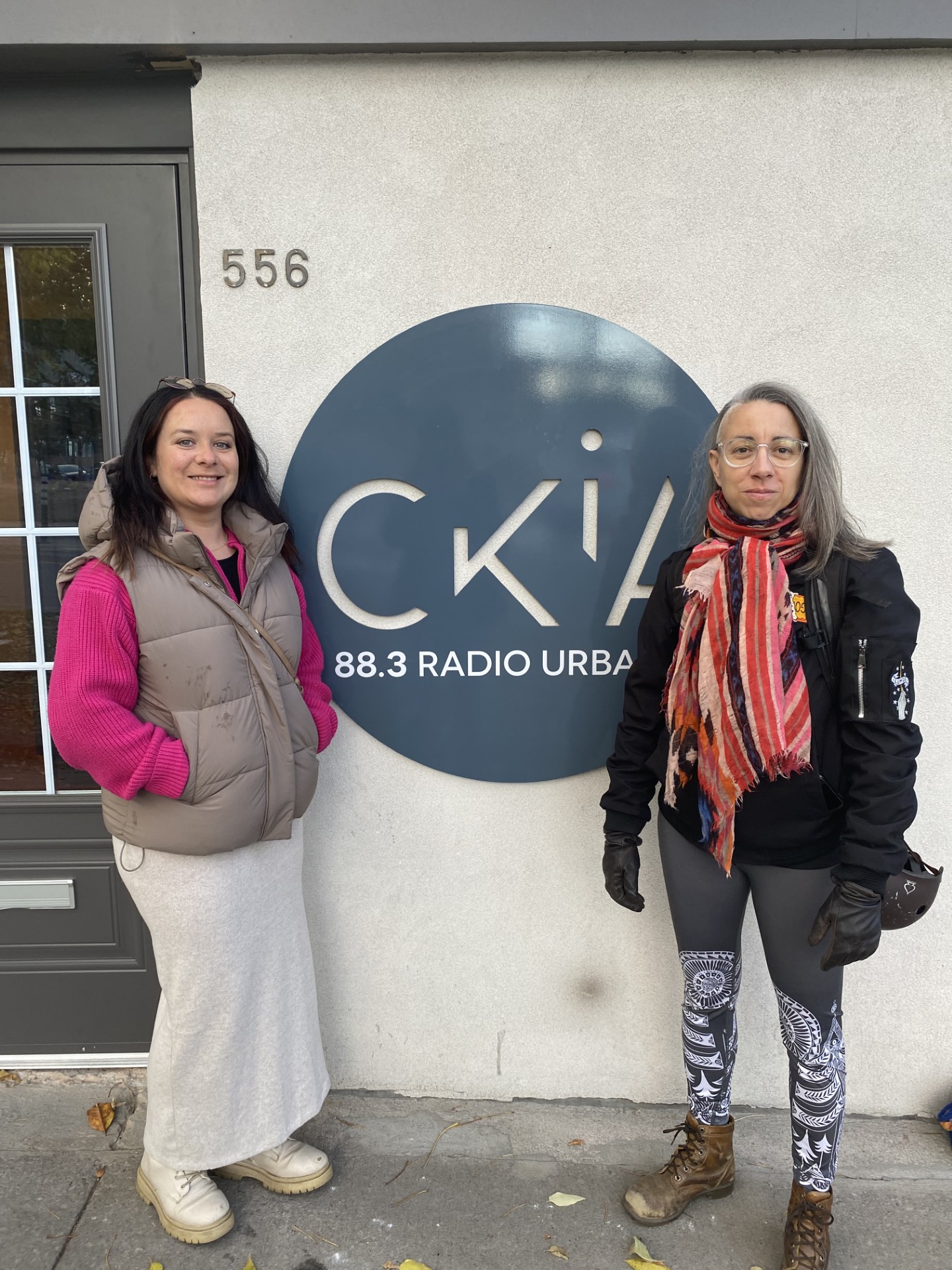 Deux membres de l'équipe de la Jonction devant l'enseigne de Ckia 88,3, la radio urbaine.
