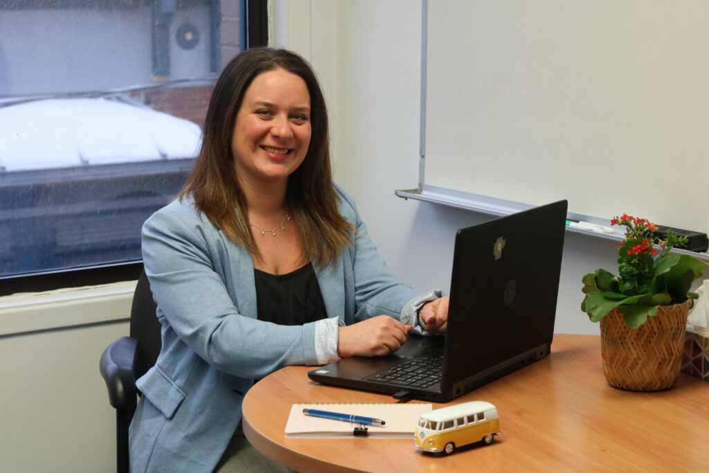 Une employée de la jonction, assise à son bureau, sourit.